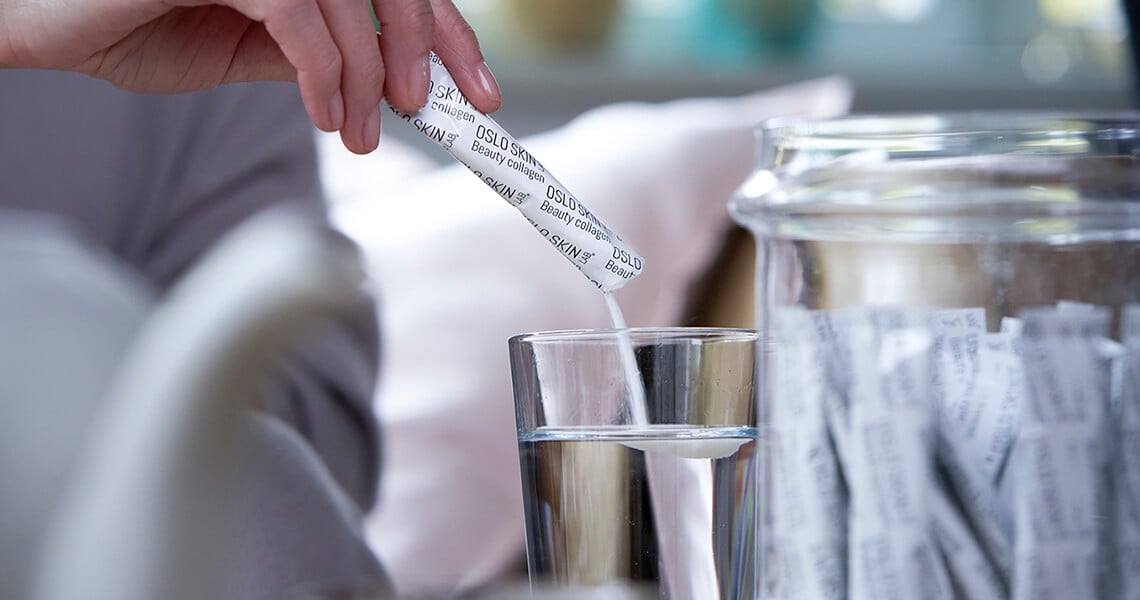 Nainen sekoittaa The Solution annospussin sisällön vesilasiin